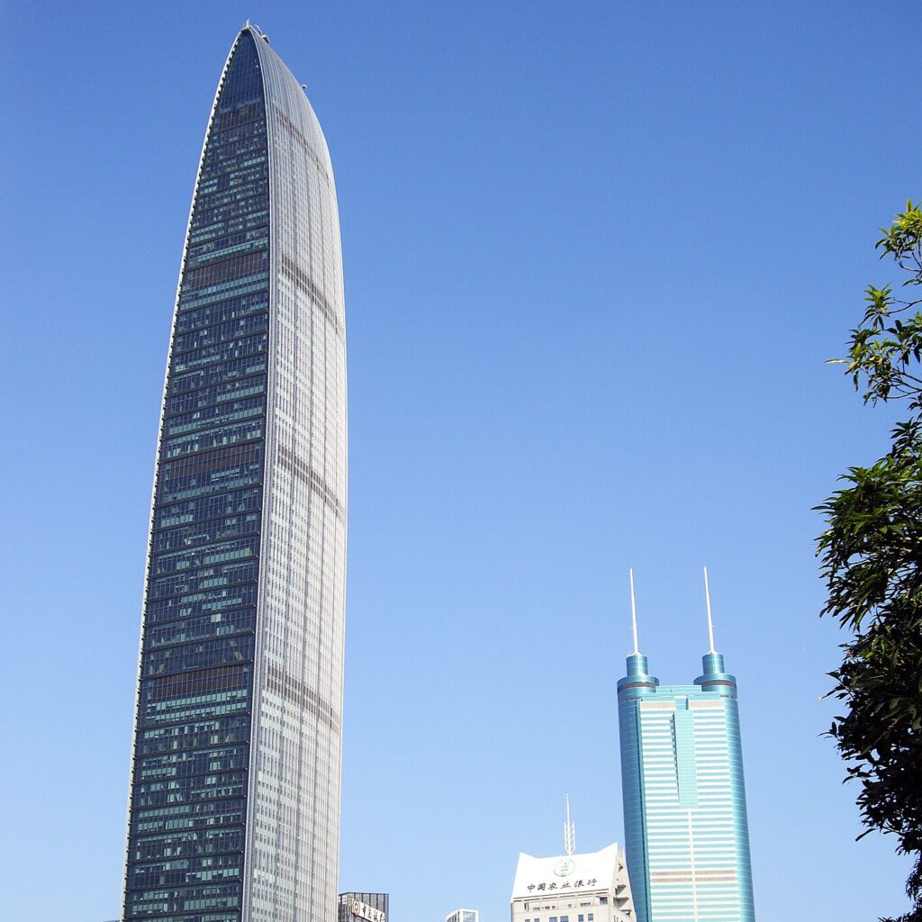 Les gratte-ciel KK100 et Diwang de Shenzhen sous un ciel bleu, entre les arbres