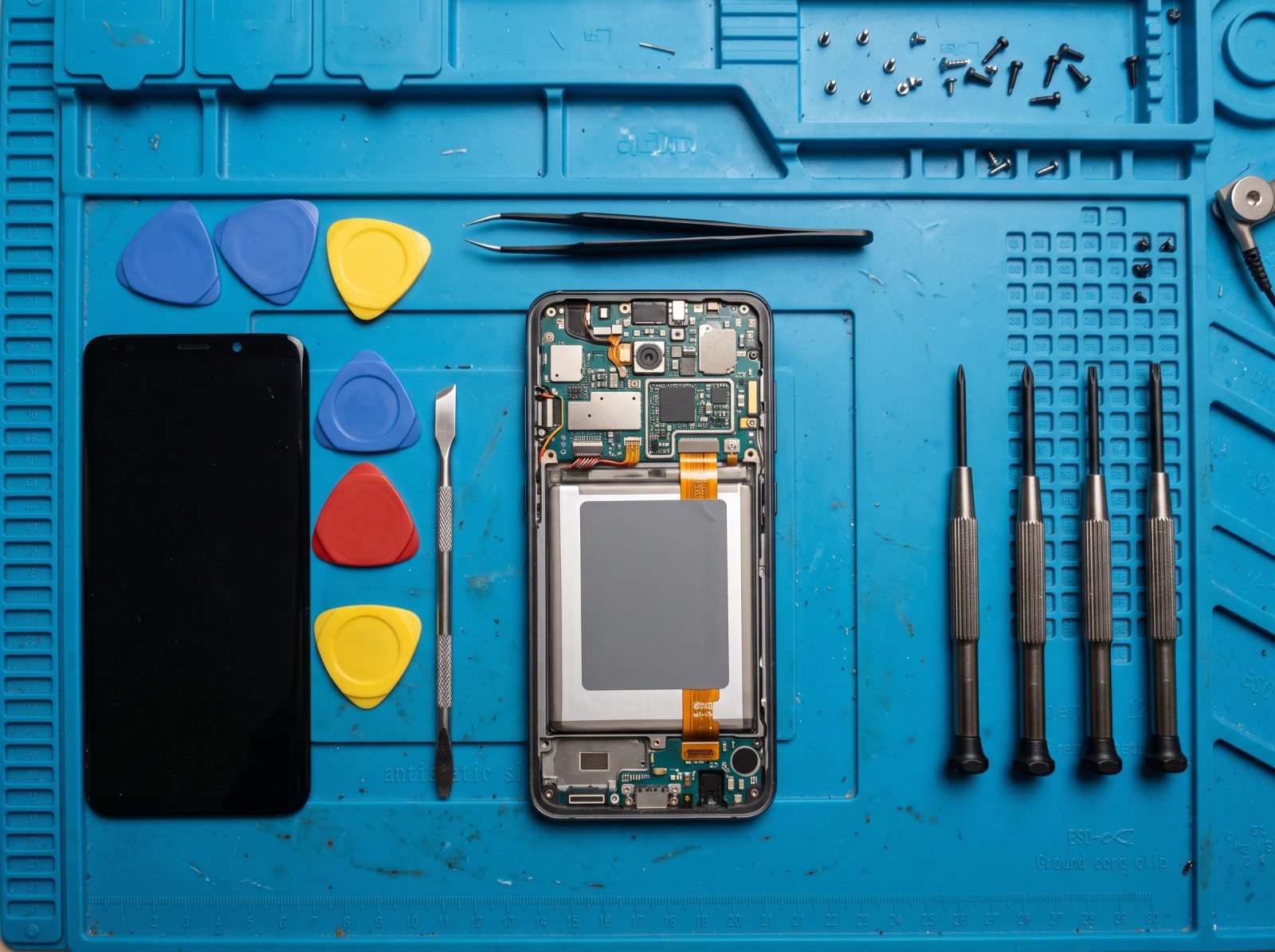 Un smartphone ouvert sur un tapis d’atelier, entouré d’outils de précision